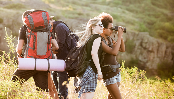 na imagem, vemos um grupo de amigos formado por duas mulheres e um homem contemplando a natureza durante trekking, uma modalidade de atividade existente dentro do turismo de aventura.